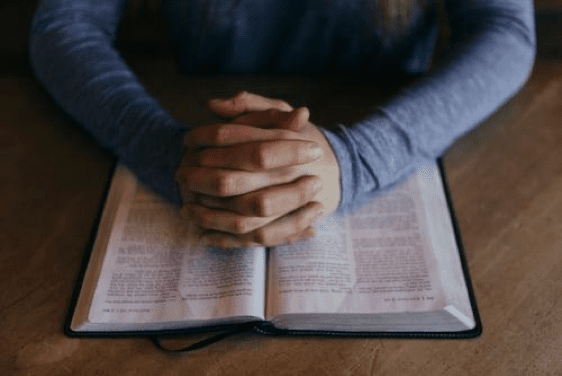 Praying hands on open Bible